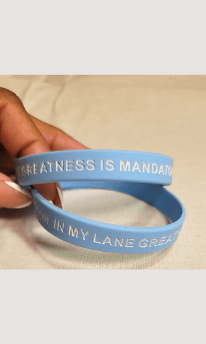 Blue bracelet with "Greatness Is Mandatory" affirmation, reminding wearers of their unique greatness.